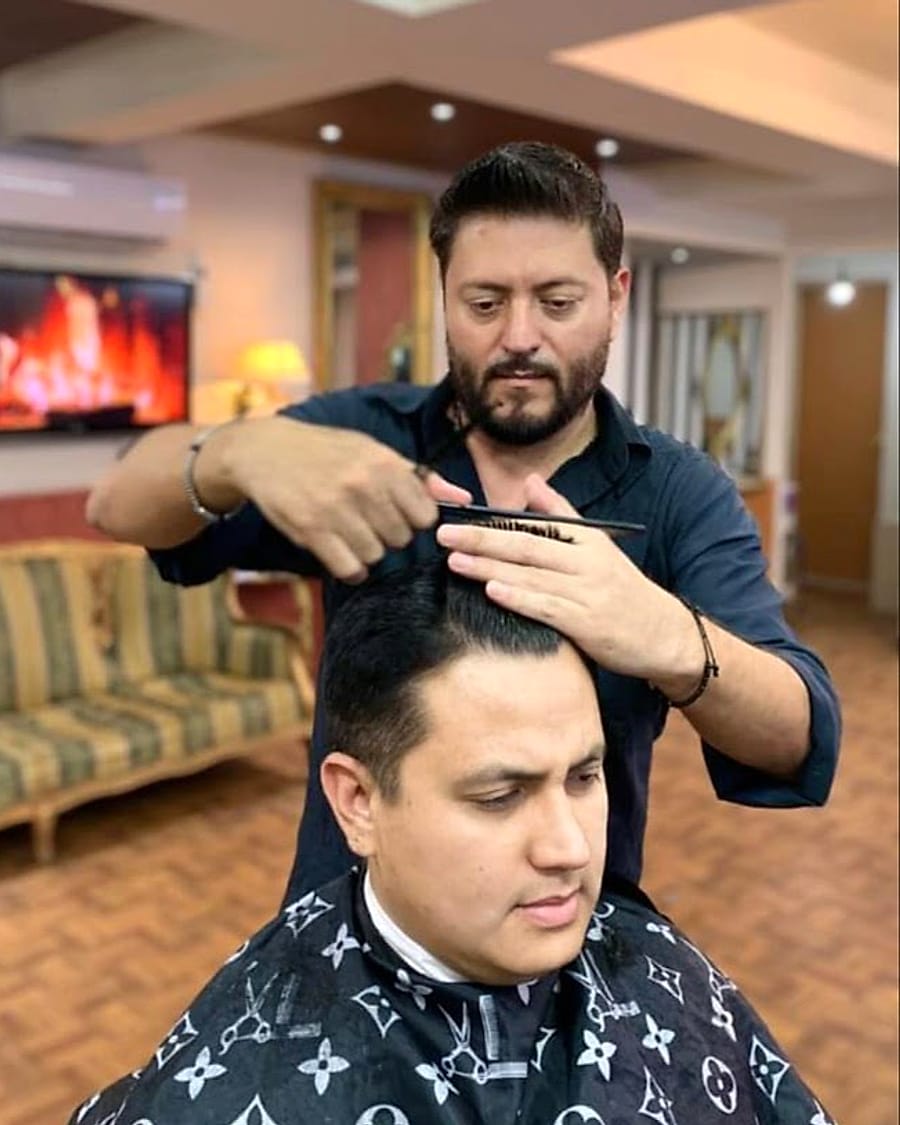 Daniel Mares cortando el cabello a un cliente